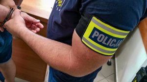 ramię mężczyzny na ramieniu opaska z napisem policja