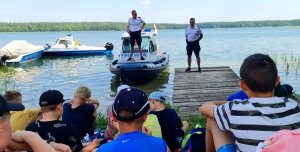 Policjanci rozmawiają z dziećmi na brzegu jeziora