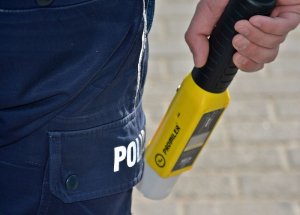 Policjant trzyma w ręce sprzęt do badania stanu trzeźwości