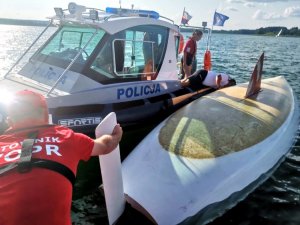 wywrócona żaglówka w tle łódź policujna