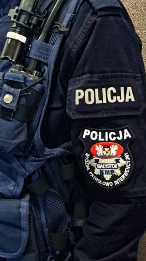 mundur policjanta na rękawie  napis policja poniżej emblemat z grafiką i napisem policja