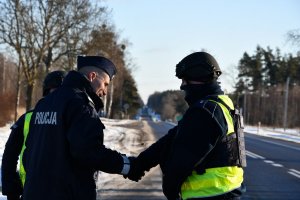 Policjanci na drodze podają sobie dłonie