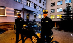 policjanci przy samochodzie w tle budynek