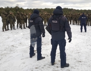 Policjanci i żołnierze stoją na śniegu.