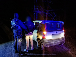 dwie osoby nocą na drodze przy pojeździe 1 osoba w mundurze z napisem policja