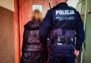 policjant przed drzwiami, obok kobieta