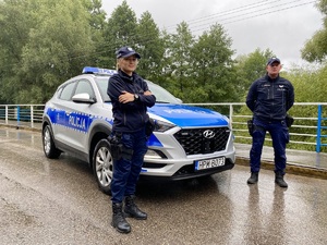 Policjanci stoją przy radiowozie na moście