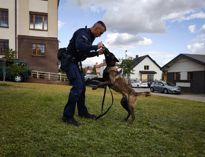 Policjant na podwórku bawi się z psem