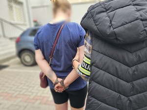 policjantka prowadzi za rękę zatrzymaną kobietę