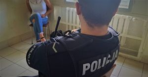 Policjant i zatrzymana kobieta siedzą w pomieszczeniu.