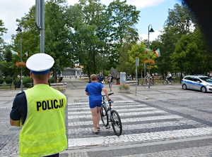 policjanci obserwują jak chłopiec prowadzi rower i przechodzi przez przejście dla pieszych