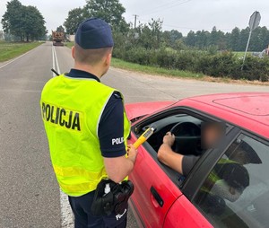 policjant na drodze bada trzeźwość kierowcy