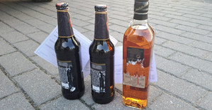 Zdjęcie przedstawia butelki z alkoholem - zawierającą poszarpane etykiety z kodem kreskówkowym