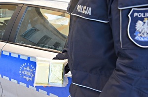 policjant w dłoni trzyma złożone koce termiczne