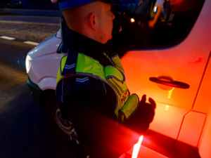policjant przy samochodzie z urządzeniem do badania stanu trzeźwości