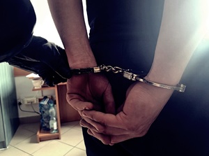 policjant i zatrzymany z kajdankami na ręce z tyłu