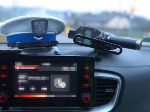 na desce rozdzielczej radiowozu leży czapka policjanta ruchu drogowego i urządzenie do mierzenia prędkości