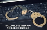 na klawiaturze komputera leżą kajdanki i obok jest napis policjanci ostrzegają nie daj się oszukać