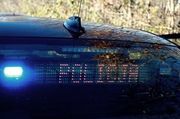 napis policja na szybie samochodu z niebieskim światłem z boku
