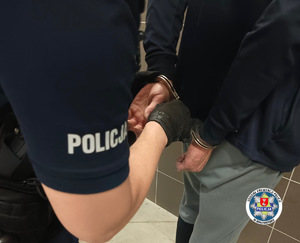 policjant zakładający zatrzymanemu kajdanki, logo OPP