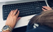 klawiatura komputerowa oraz widoczne dłonie na niej
