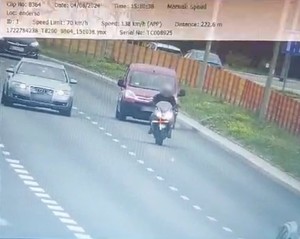 dwa samochody jadące ulicą przed nimi motocykl. Jest to zdjęcie fotoradaru policyjnego. Na górze są napisy w języku angielskim speed limit 70 km/h i speed 138 km/h