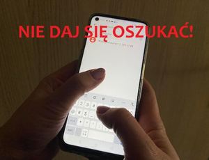 widać ekran telefonu komórkowego trzymane dłonie oraz czerwony napis nie daj się oszukać