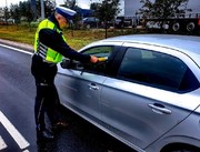 policjant bada kierowce siedzącego w pojeździe