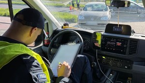 policjant w radiowozie wypełniający niezbędną dokumentację. w Oddali zatrzymany do kontroli Volkswagen