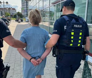 zatrzymana kobieta prowadzona przez plicjantów