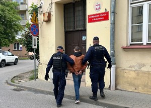 poszukiwany mężczyzna prowadzony przez policjantów do komisariatu