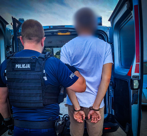 policjant prowadzi osobę zatrzymaną