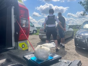 zatrzymany w kajdankach a obok policjant . na pierwszym planie biały proszek- amfetamina