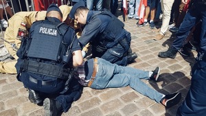 policjanci udzielający pomocy mężczyźnie, wraz z funkcjonariuszami Państwowej Straży Pożarnej.