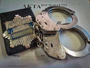 na okładce akt dochodzenia leżą kajdanki i legitymacja policyjna