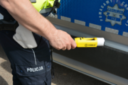policjant z urządzeniem do mierzenia zawartości alkoholu w wydychanym powietrzu stojący przy radiowozie