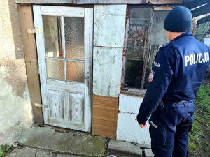 policjant stojący przy drzwiach pustostanu