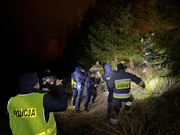 służby szukające po zmroku w lesie osoby zaginionej