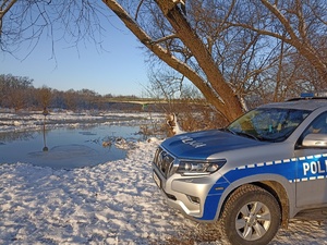 radiowóz a w tle zbiornik wodny i śnieg