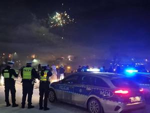 policjanci w tle budynki i fajerwerki