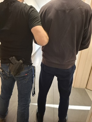 mężczyzna stojący tyłem z policjantem obok