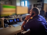 policjant dyżurny siedzący przy monitorach ze słuchawką przy uchu