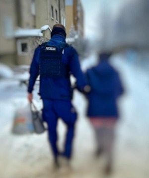 policjant idzie trzymając pod ramię kobietę