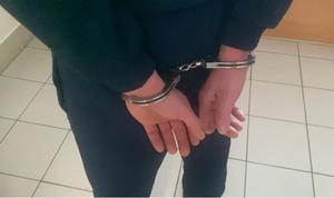 osoba w kajdankach zapiętych na nadgarstkach z tyłu