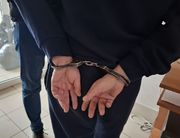 osoba w kajdankach zapiętych na nadgarstkach z tyłu