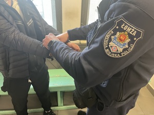 osoba, której policjant zapina kajdanki na nadgarstki
