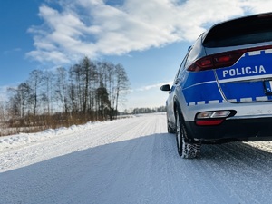 policyjny radiowóz zaparkowany na poboczu ośnieżonej drogi