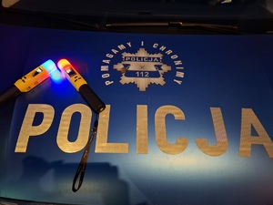 na niebieskim tle napis policja pomagamy i chronimy oraz dwa urządzenia do mierzenia zawartości alkoholu w organizmie