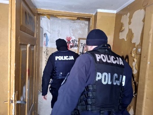 dwóch policjantów w budynku przechodzących przez drzwi z jednego pomieszczenia do drugiego