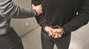 osoba w kajdankach z policjantem trzymającym za ramię, widziani od tyłu